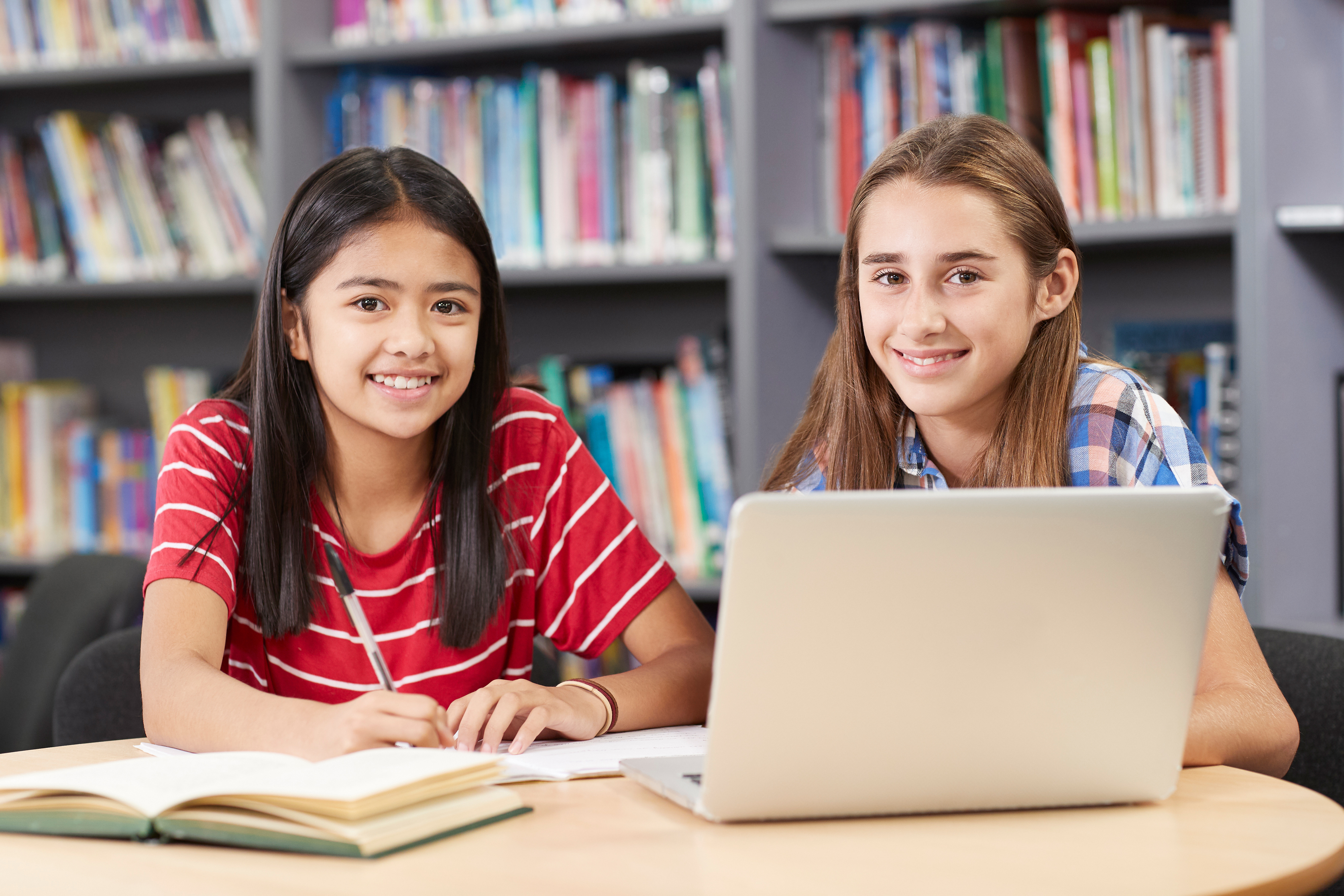 Portrait Of Two Female High School Students Working At Laptop In Library